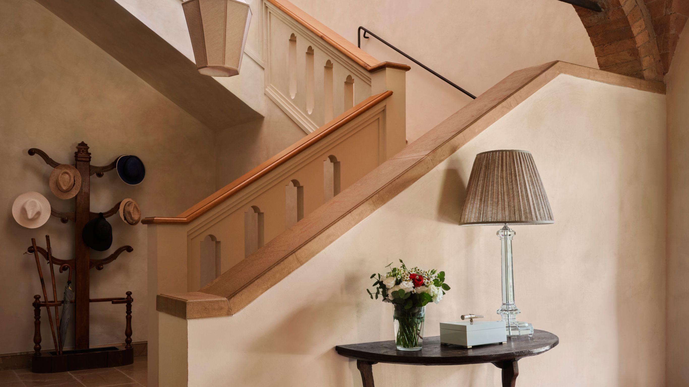 A staircase with a wooden handrail and a  decorative coat rack with hats